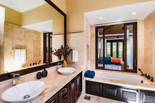 a bathroom with two sinks and a tub and a mirror at Luxury Vacation Rentals At Hacienda Pinilla in Tamarindo