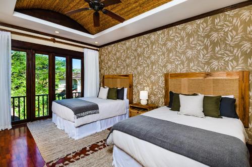 a bedroom with two beds and a balcony at Luxury Vacation Rentals At Hacienda Pinilla in Tamarindo