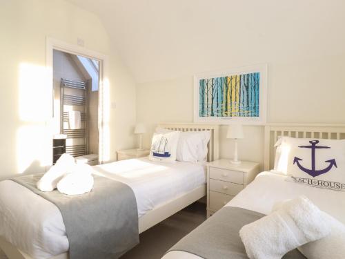 um quarto branco com 2 camas e uma janela em Rock Cottage em Bamburgh