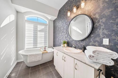 een badkamer met een bad, een wastafel en een spiegel bij Modern 4 Level home-Game room/Parking/Near Airport in Mississauga