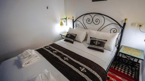 a bed with black and white pillows on it at Riad Green House in Fès