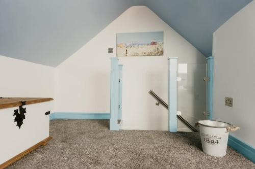 an attic room with a door and a bucket at The Sea Deck Apartment - Westbrook Bay Beach - By Goldex Coastal Breaks in Kent