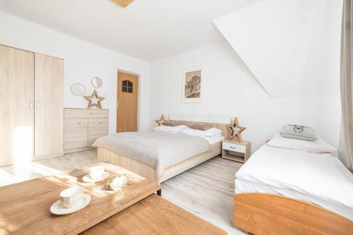 a white bedroom with two beds and a table at Willa Dunajec in Zakopane