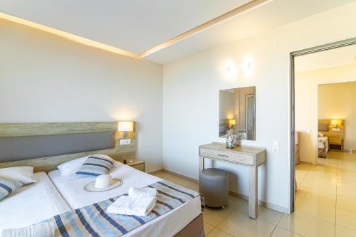 a bedroom with a bed and a desk and a mirror at Theo Star Beach Hotel in Malia