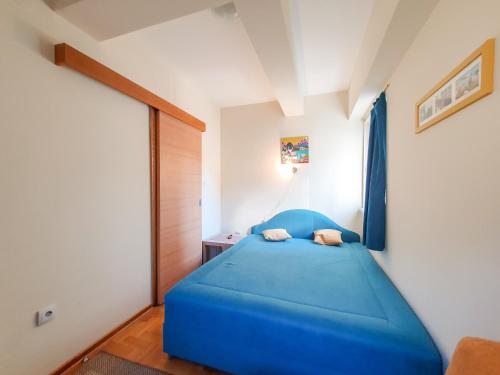 - une chambre avec un lit bleu dans l'établissement Apartman Cvejic - Suncani apartmani, à Brzeće