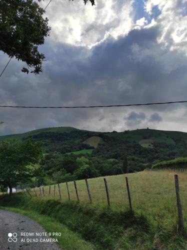 une clôture sur le côté d'un champ avec une colline dans l'établissement Maison individuelle au cœur de la Soule au pays basque, à Musculdy
