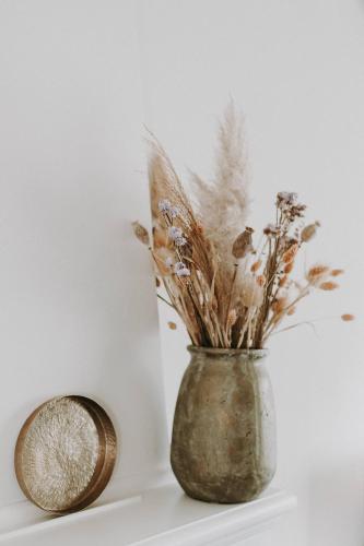 a vase with dried flowers in it next to a clock at Charmeverblijf Juliette in Kasterlee