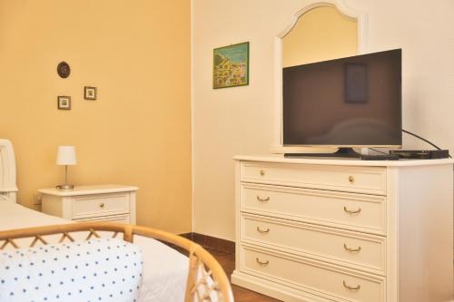 a bedroom with a dresser with a television on it at Villa La Caletta in Carloforte