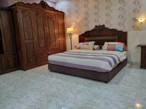 a bedroom with a large bed and a wooden cabinet at House of Ken in Yogyakarta