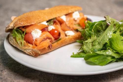a sandwich and a salad on a white plate at Apollon Windmill Boutique Hotel - Adults Only in Kos Town