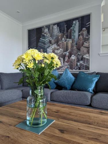 a vase with yellow flowers on a table in a living room at Beautiful 2 bedroom flat overlooking golf course in Carnoustie