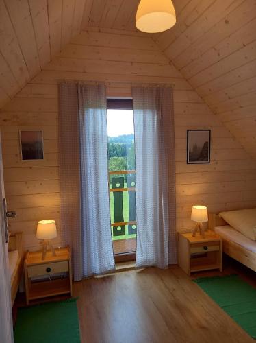 a room with two lamps and a window in a cabin at Leśna Przystań - Domki całoroczne in Grywałd