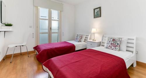 2 camas en una habitación blanca con sábanas rojas en Modern Apartment U2 - Zias with lovely views in heart of Aphrodite Hills, en Kouklia