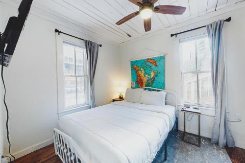 a bedroom with a white bed with a ceiling fan at The Pink House on Main - Lower in Eureka Springs