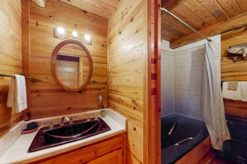 a bathroom with a sink and a shower and a mirror at Charlie's Ol' Fishing Cabin in Eureka Springs