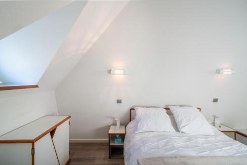 een witte slaapkamer met een bed en een tafel bij Ty Corn in Bénodet