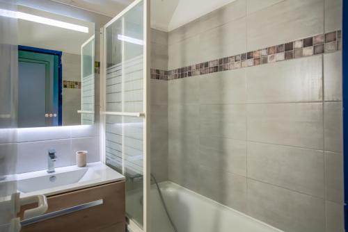 een badkamer met een bad, een wastafel en een spiegel bij Ty Corn in Bénodet