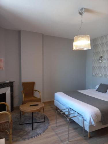 a bedroom with a bed and a chair and a fireplace at Hotel Restaurant de la Poste in Saint-Just-en-Chevalet