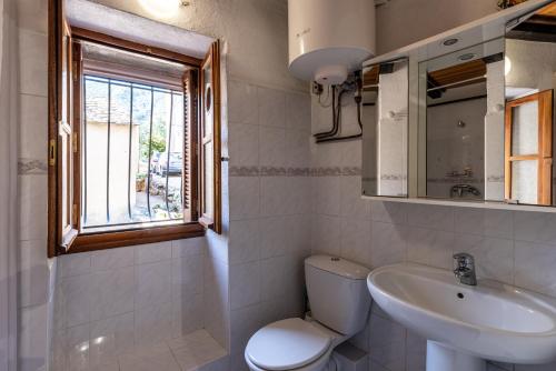a bathroom with a toilet and a sink and a window at Pentone in Cervione