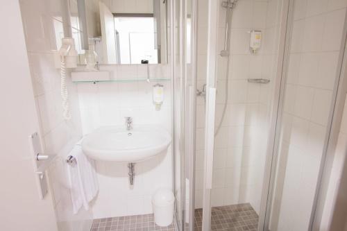 a white bathroom with a sink and a shower at Senator Hotel in Frankfurt/Main