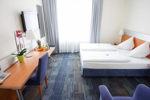 una camera d'albergo con letto e scrivania di Senator Hotel a Francoforte sul Meno