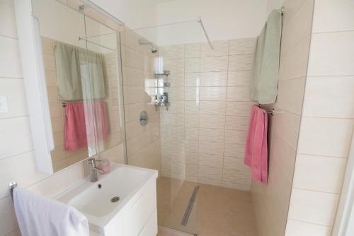 uma casa de banho com um lavatório e um chuveiro com toalhas cor-de-rosa em K33 em Tiszaújváros