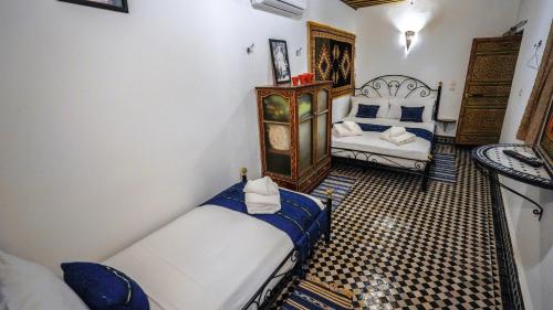 a room with two beds and a chair in it at Riad Green House in Fès