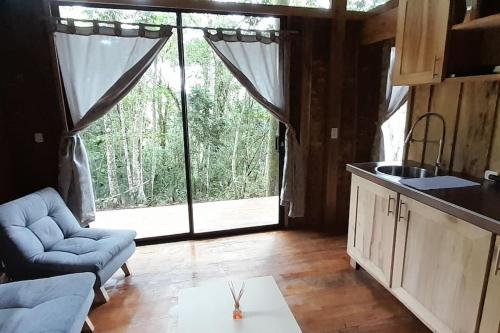 een woonkamer met een groot raam en een keuken bij Zen Oasis del Bosque, ¡A place to reconnect! in Calima