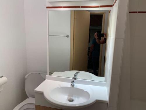 un uomo che scatta una foto di un bagno con lavandino di T3 idéal ski et randonnée en famille a Cauterets