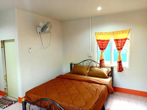 een slaapkamer met een bed en een raam met een ventilator bij TR Bungalow in Ban Tha Rua