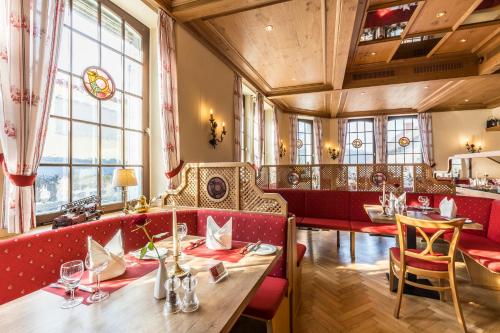 a restaurant with a long table and red booths at Wellness Privathotel Post an der Therme in Badenweiler