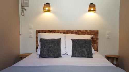 a bed with two black and white pillows and two lights at Hôtel Terminus in Luz-Saint-Sauveur
