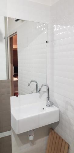 a white bathroom with a sink and a mirror at Hôtel Terminus in Luz-Saint-Sauveur