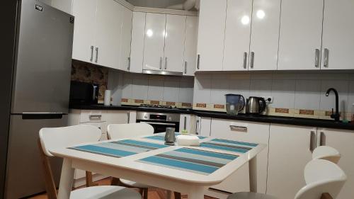 a kitchen with white cabinets and a table and chairs at Запорізька 19 City Rooms in Bila Tserkva