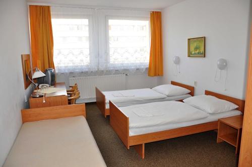 a bedroom with two beds and a desk and a window at Tatra Hotel in Poprad
