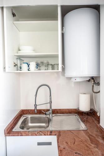 a kitchen with a sink and white cabinets at BeniBeachHouse in Benidorm
