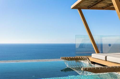 a resort infinity pool with a hammock and the ocean at Mani Theasis in Stoupa