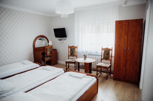 a bedroom with two beds and a table and a tv at Pokoje gościnne Biała Dama in Mławka
