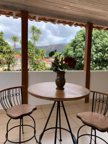 una mesa y sillas con un jarrón de flores en un porche en Pousada Villa Real, en Tiradentes
