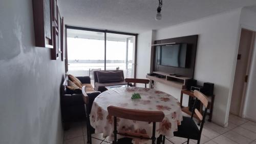 sala de estar con mesa, sillas y TV en Departamento Avenida Del Mar, en La Serena