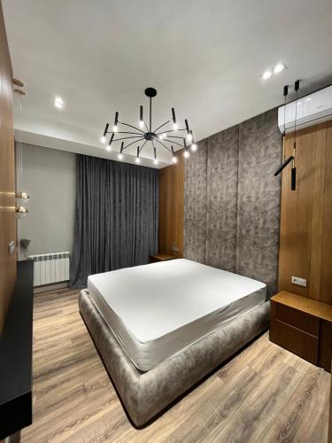 a bedroom with a large bed and a chandelier at Ташкент сити in Tashkent