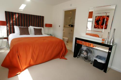 a bedroom with a bed with an orange blanket and a fireplace at Chelmsford Serviced Apartments in Chelmsford