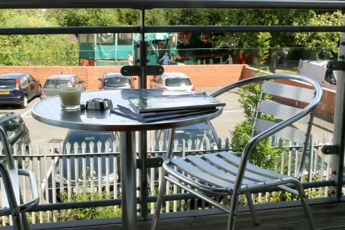 una mesa y una silla en un balcón con una taza de café en Chelmsford Serviced Apartments, en Chelmsford