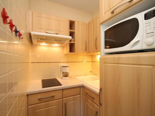 une petite cuisine avec un micro-ondes et un évier dans l'établissement Mont-Dore: Duplex 3 pièces avec balcon, parking - FR-1-608-161, à Le Mont-Dore