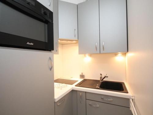 une petite cuisine avec un évier et un micro-ondes dans l'établissement Charmant T2 avec Balcon et Parking à 220m du Centre du Mont-Dore - FR-1-608-189, à Le Mont-Dore