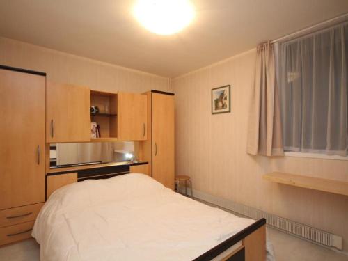 - une petite chambre avec un lit et un four micro-ondes dans l'établissement Charmant T2 avec Balcon et Parking à 220m du Centre du Mont-Dore - FR-1-608-189, à Le Mont-Dore