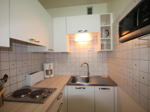 une cuisine avec des armoires blanches et un évier dans l'établissement Charmant T2 avec Balcon et Wi-Fi au Mont-Dore, Proche Centre et Thermes - FR-1-608-193, à Le Mont-Dore
