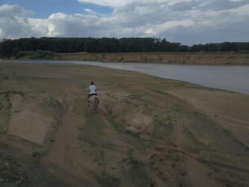 a person riding a horse on a dirt road near a body of water at La Viña. Casa rural en el campo in Tordera