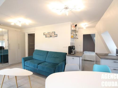 un salon avec un canapé bleu et une cuisine dans l'établissement Appartement T3 au Mont-Dore, hyper centre, proche thermes, bien équipé, max 4 pers, petit chien ok. - FR-1-608-227, à Le Mont-Dore