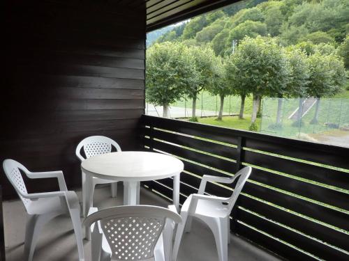 d'une table et de chaises blanches sur un balcon avec fenêtre. dans l'établissement T2 avec balcon, parking privé, proche forêt, Mont-Dore - FR-1-608-212, à Le Mont-Dore